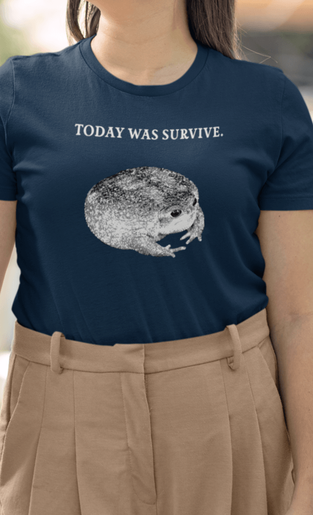 A woman wears a navy T-shirt featuring a cute toad, saying &quot;today was survive.&quot;