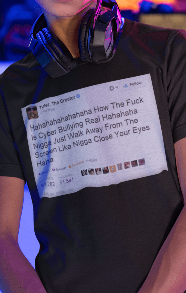 A boy wearing a black T-shirt with a Tyler The Creator Tweet written &quot;Hahaha How The F*ck Is Cyber Bullying Real Haha N*gga Just Walk Away From The Screen, Like, N*gga Close Your Eyes Haha&quot;.