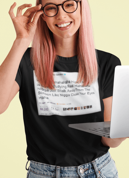 A woman holding a computer wearing a black T-shirt with a Tyler The Creator Tweet written &quot;Hahaha How The F*ck Is Cyber Bullying Real Haha N*gga Just Walk Away From The Screen, Like, N*gga Close Your Eyes Haha&quot;.