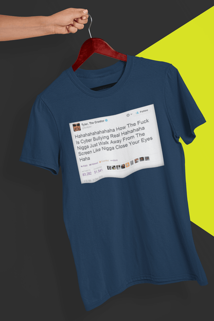 A navy-blue T-shirt with a Tyler The Creator Tweet written &quot;Hahaha How The F*ck Is Cyber Bullying Real Haha N*gga Just Walk Away From The Screen, Like, N*gga Close Your Eyes Haha&quot;, held by a hand against a split black and yellow background.