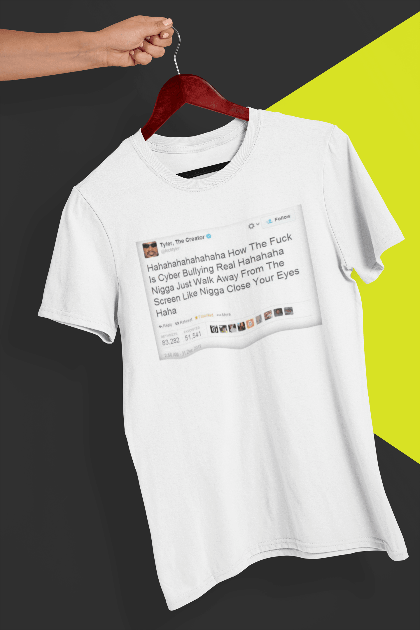 A white T-shirt with a Tyler The Creator Tweet written &quot;Hahaha How The F*ck Is Cyber Bullying Real Haha N*gga Just Walk Away From The Screen, Like, N*gga Close Your Eyes Haha&quot;, held by a hand against a split black and yellow background.