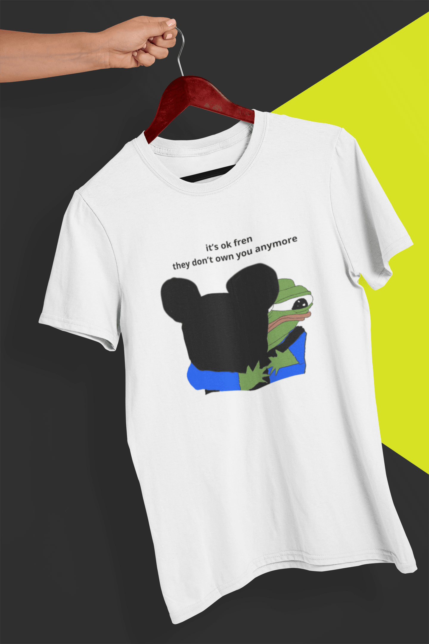 A white T-shirt with Mickey Mouse hugging a cute Apu in the middle, saying &quot;it&#39;s ok fren, they don&#39;t own you anymore&quot;, held by a hand against a split black and yellow background.